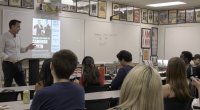 A man stands at a podium giving a presentation to a classroom of college students. A slide on the screen behind him promotes an event featuring Cameron Smyth on Tuesday, September 23. The students are seated at desks, some taking notes or using their phones. The classroom walls are decorated with historical and political posters, and a whiteboard behind the speaker displays the club's Instagram handle "@coc_polsa_club" with the word "FOLLOW" written below.