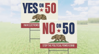 Alt text: "Two campaign yard signs on a grassy field. One sign reads 'YES on 50 – Fair Elections' and the other reads 'NO on 50 – Stop the Political Power Grab,' both featuring a bear graphic and red, white, and blue colors."