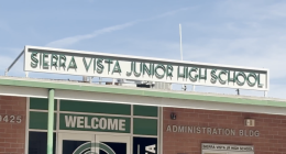 The front entrance of Sierra Vista Junior High School showing the school’s name sign above the building and a “Welcome” sign on the glass doors of the administration building.