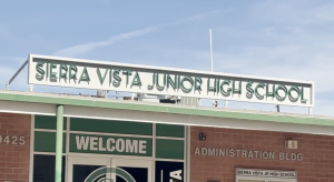 The front entrance of Sierra Vista Junior High School showing the school’s name sign above the building and a “Welcome” sign on the glass doors of the administration building.