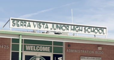 The front entrance of Sierra Vista Junior High School showing the school’s name sign above the building and a “Welcome” sign on the glass doors of the administration building.