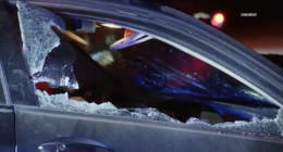 Broken passenger side window of a dark sedan that was in a car accident.