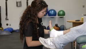 A student Athletic trainer wraps a person left ankle with tape in a training room at Canyon High School