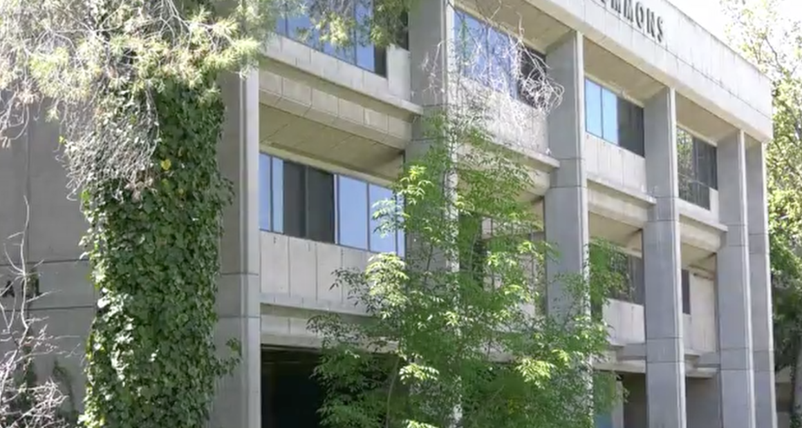 The building is a prominent example of Brutalist architecture, a style characterized by its heavy use of raw, board-formed concrete and functional, geometric shapes. In the image, you can see the distinctive vertical concrete columns and the "COMMONS" signage at the top, along with the characteristic ivy-covered pillar that has become a staple of the building's aesthetic.