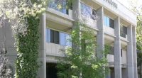 The building is a prominent example of Brutalist architecture, a style characterized by its heavy use of raw, board-formed concrete and functional, geometric shapes. In the image, you can see the distinctive vertical concrete columns and the "COMMONS" signage at the top, along with the characteristic ivy-covered pillar that has become a staple of the building's aesthetic.