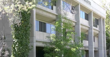 The building is a prominent example of Brutalist architecture, a style characterized by its heavy use of raw, board-formed concrete and functional, geometric shapes. In the image, you can see the distinctive vertical concrete columns and the "COMMONS" signage at the top, along with the characteristic ivy-covered pillar that has become a staple of the building's aesthetic.