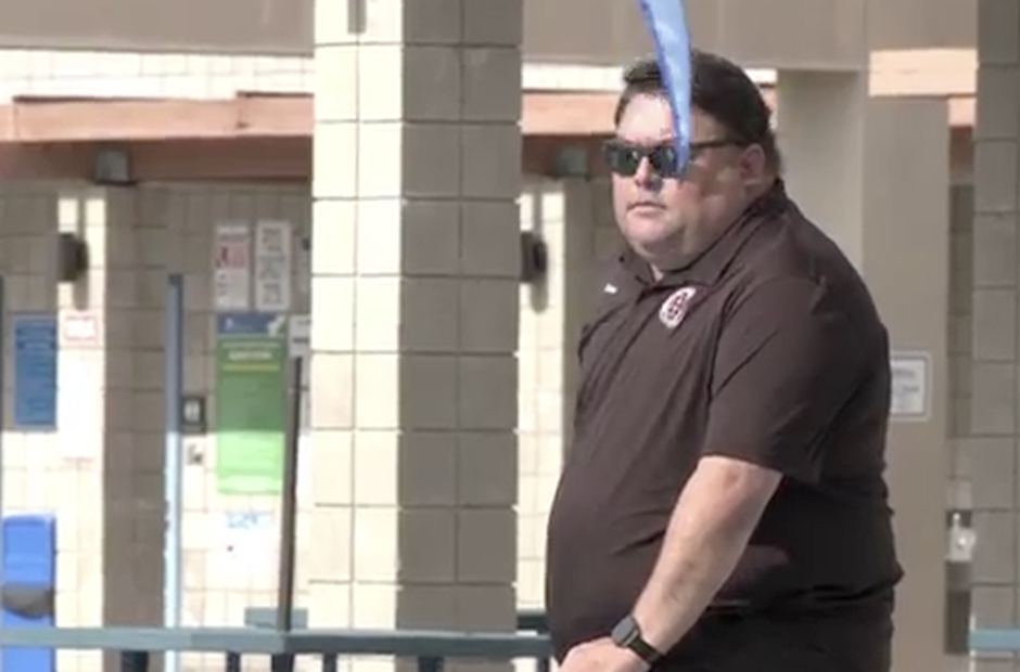 A Sean Kakumu sunglasses and a dark polo shirt stands outdoors near tiled columns and a railing, with a blue object partially obscuring the foreground.