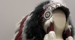 This image features a Native American-style headdress displayed on a neutral-toned mannequin head. The piece is highly detailed, showcasing traditional craftsmanship through various textures and materials.