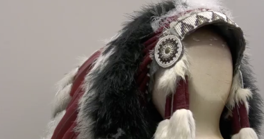 This image features a Native American-style headdress displayed on a neutral-toned mannequin head. The piece is highly detailed, showcasing traditional craftsmanship through various textures and materials.