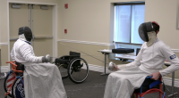 Two wheelchair fencers in protective gear face off with foils during a match, demonstrating adaptive sports at the Triumph Foundation’s Wheelchair Sports Festival.