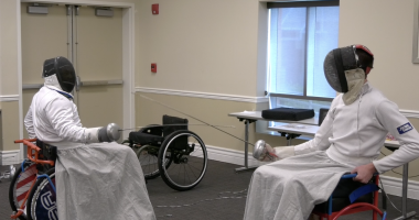 Two wheelchair fencers in protective gear face off with foils during a match, demonstrating adaptive sports at the Triumph Foundation’s Wheelchair Sports Festival.